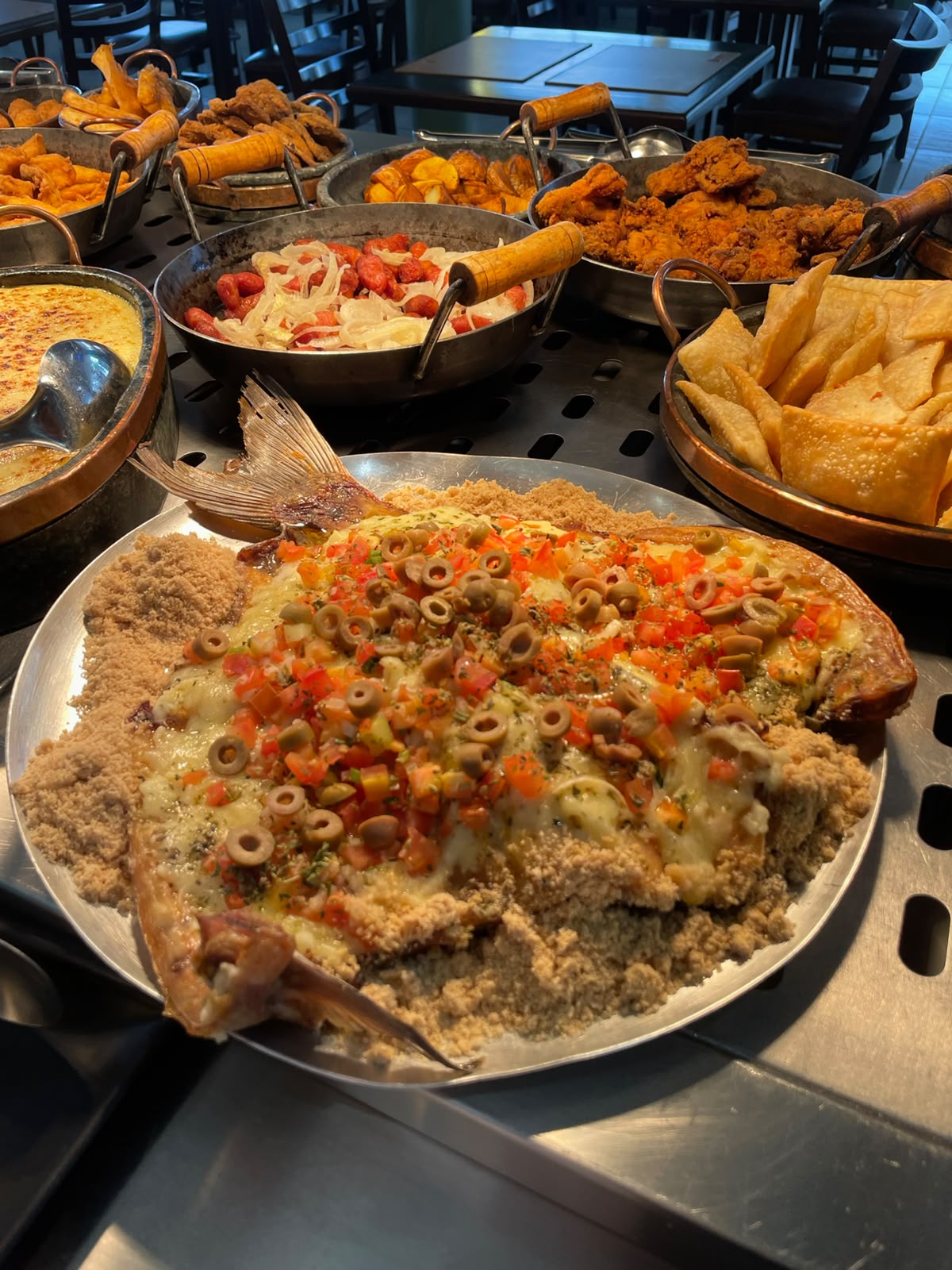 Peixe assado gratinado com queijo, azeitonas e tomate sobre farofa no buffet