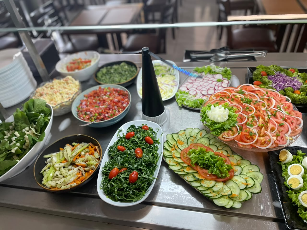 Estação de saladas com folhas frescas, tomate, pepino, rúcula e vinagretes