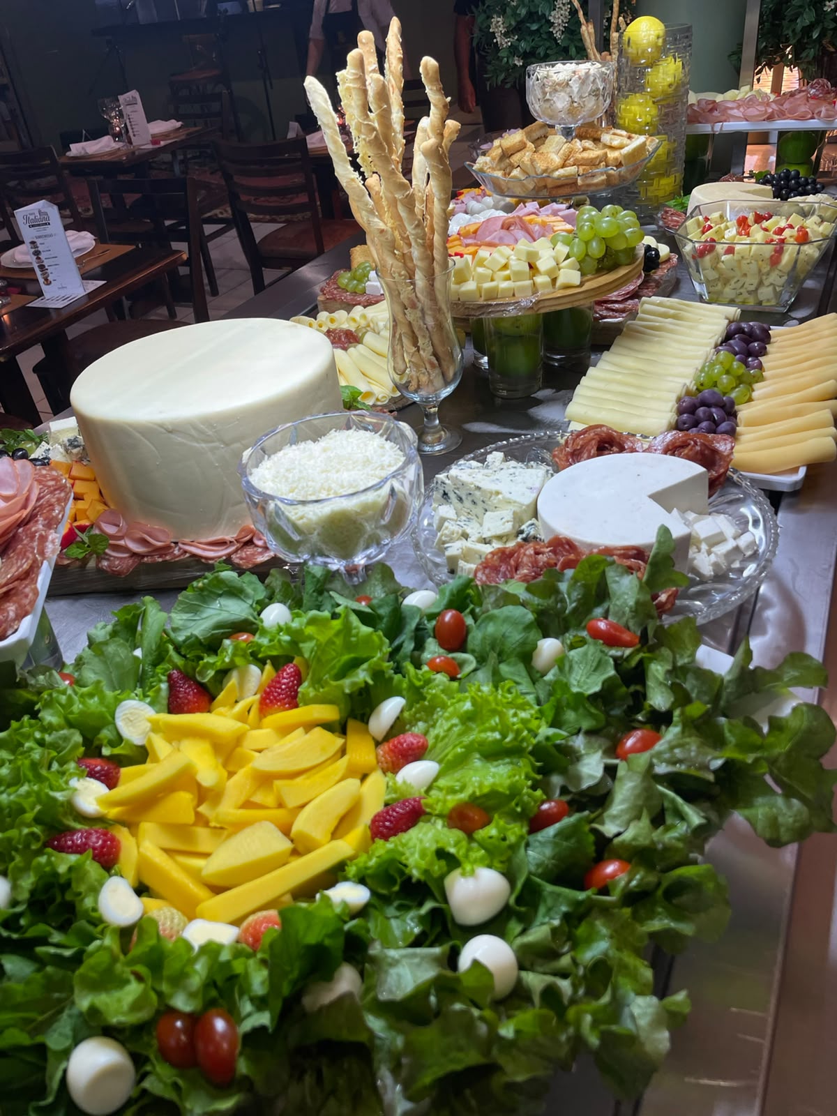 Mesa italiana com queijos, grissinis, uvas e saladas frescas decoradas